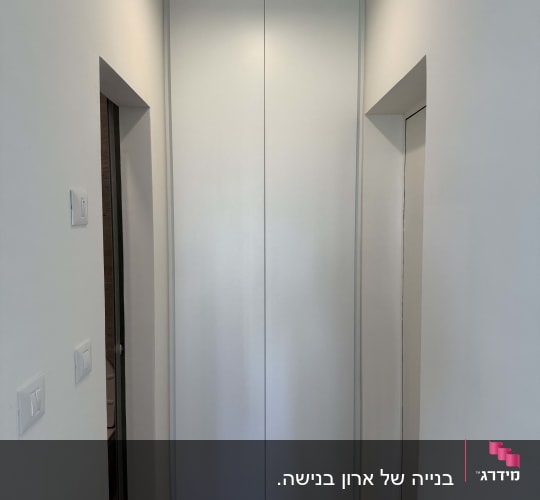 ארון קיר לבן במסדרון עם רצפת עץ